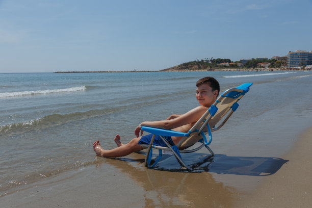 孩子坐在海边的沙滩椅上图片下载