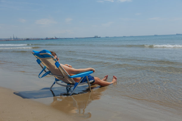 孩子坐在海边的沙滩椅上图片下载