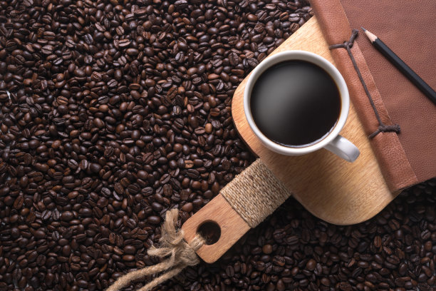 白色杯子里装着咖啡，木头架子上放着笔记和铅笔图片下载