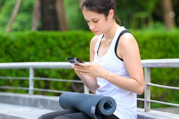 女人在绿色公园里用智能手机享受和放松户外图片下载