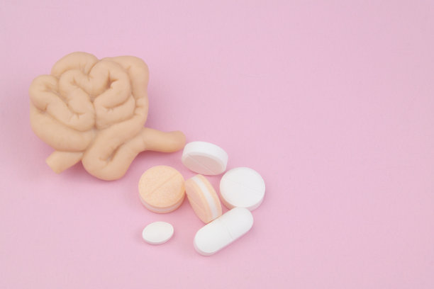 粉红色背景上的小肠和药物。图片下载