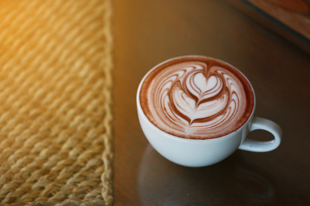 咖啡师用手往咖啡杯里倒热牛奶，准备做拉花。咖啡师的多种技能，使咖啡饮料在咖啡店。专业提供冷热饮料，随时为顾客服务。图片下载