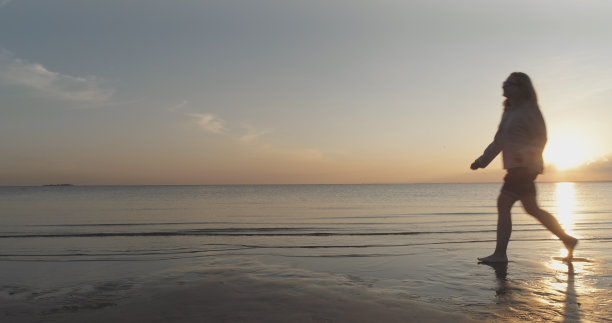 日落时分，赤脚少女在波罗的海海滩上行走的航拍图片下载