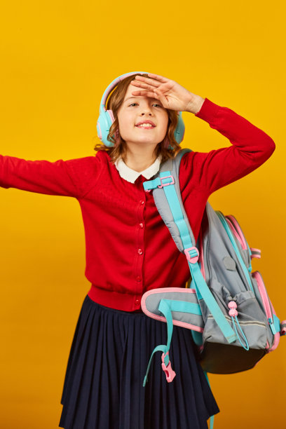 快乐的女学生背着书包，戴着耳机玩得很开心图片下载