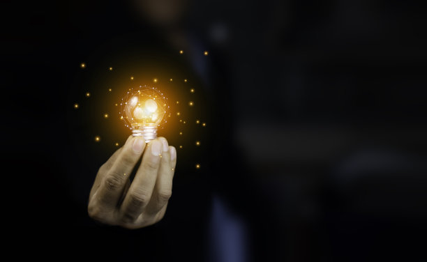 穿着黑色背景西装的商人手里拿着灯泡。成功的想法和创新的新想法或灵感，基于互联网数据的技术，大数据。图片下载