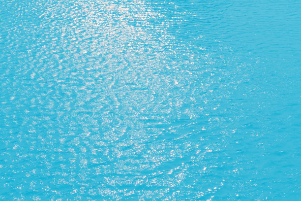 蓝蓝的水面上泛起涟漪。散焦模糊透明蓝色透明平静水面纹理与飞溅和气泡。水波与闪亮的图案纹理背景。图片下载