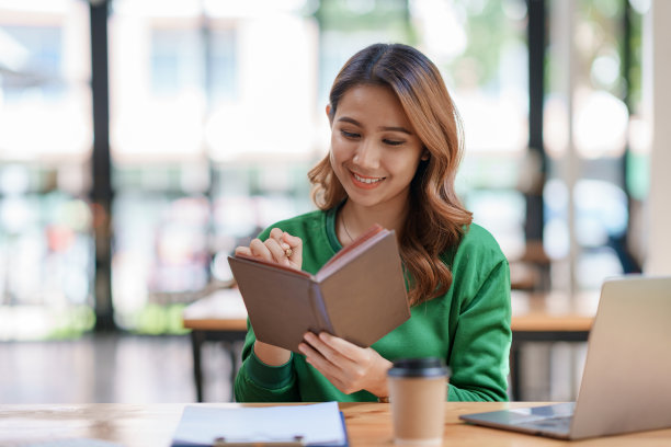 美丽的年轻亚洲女学生正在读书，并记下他们的学习和学习细节，以便向老师提交报告。图片下载