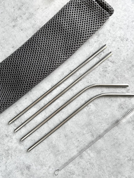 可重复使用的不锈钢吸管和清洁刷装在灰色的袋子里，灰色的背景图片下载