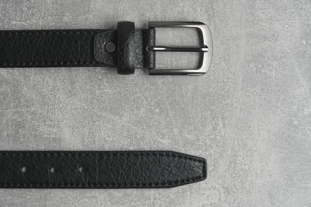 黑色男子皮带与金属徽章灰色混凝土背景。图片下载