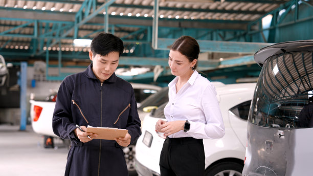 西装革履的专业修理工在汽车修理厂工作。修理工和顾客谈了谈，同意把车修好。发合同取车。两人满意地握了握手。图片下载