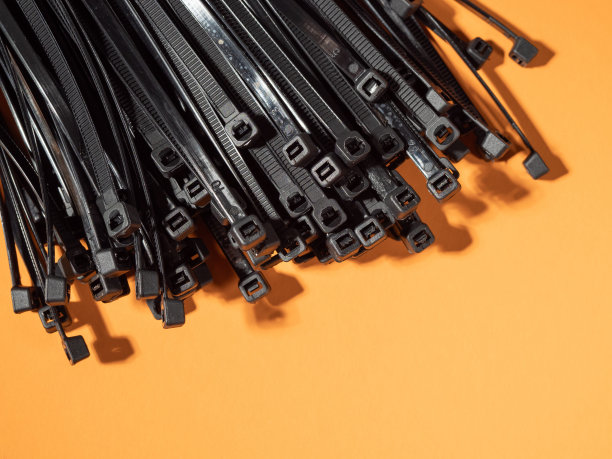 橙色背景上的黑色塑料领带。图片下载