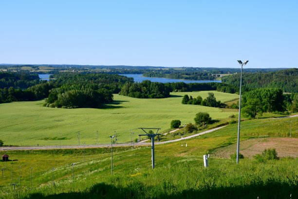 在波兰的一个阳光明媚的夏日，从一个覆盖着树木、森林、沼泽、田野和其他植物的高山俯瞰远处广阔而清澈的湖泊或河流图片下载