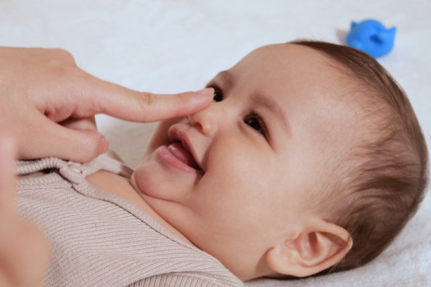 快乐的小男孩躺着，妈妈的手按着她的脸颊图片下载