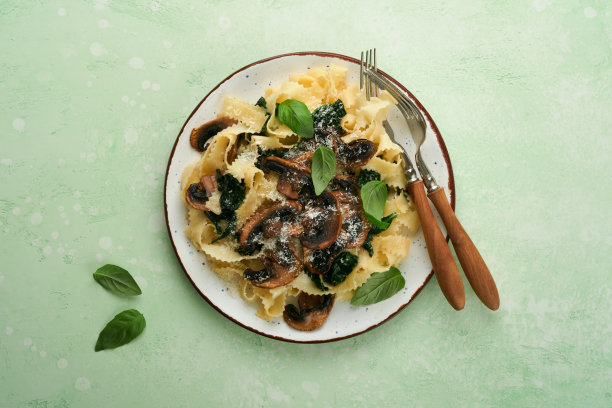 奶油阿尔弗雷多意大利面。意大利意式宽面，配蘑菇、鸡肉、菠菜、罗勒和奶油酱，背景为绿色石头或混凝土。传统的意大利菜。平的。本空间图片下载