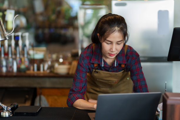 人像，面包店咖啡馆的店主白天在咖啡馆里用笔记本电脑工作，这是在寻找更多关于咖啡馆的信息添加，或者寻找新的菜单添加商店，使其更有趣独特。图片下载