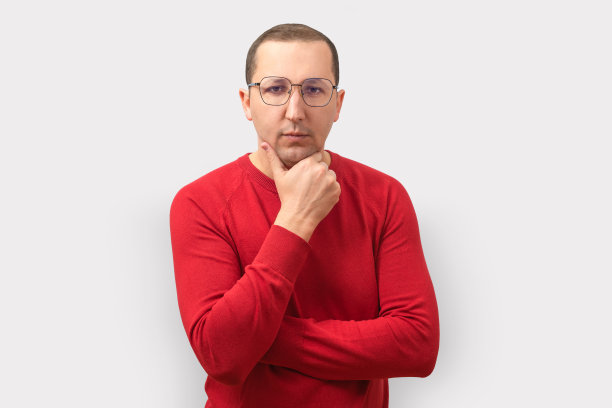 自信的男人看着灰色背景下的相机。图片下载