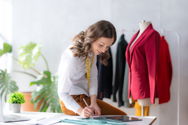 美女设计师正在根据流行趋势起草衣服，缝制得漂亮。图片下载
