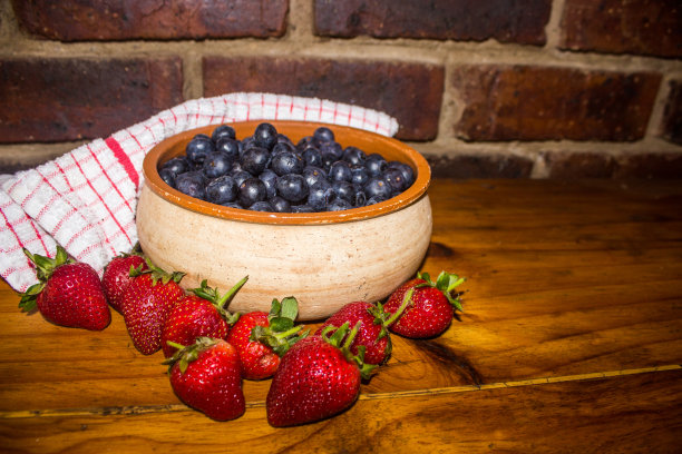 一碗蓝莓，周围是饱满的红草莓图片下载