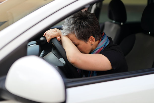 老女人睡在车的方向盘上。图片下载
