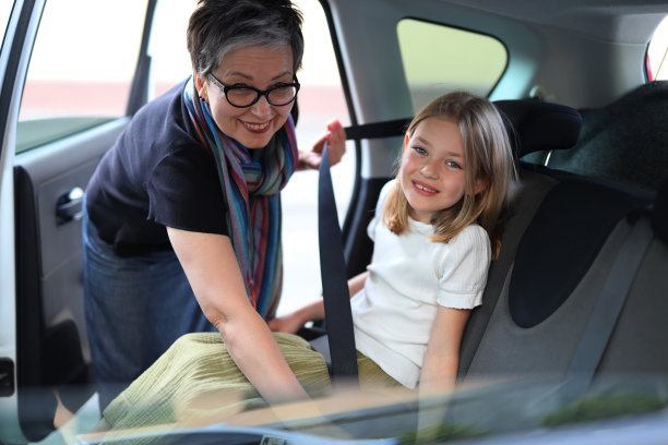 快乐的祖母把孙女扣在汽车后座上。图片下载