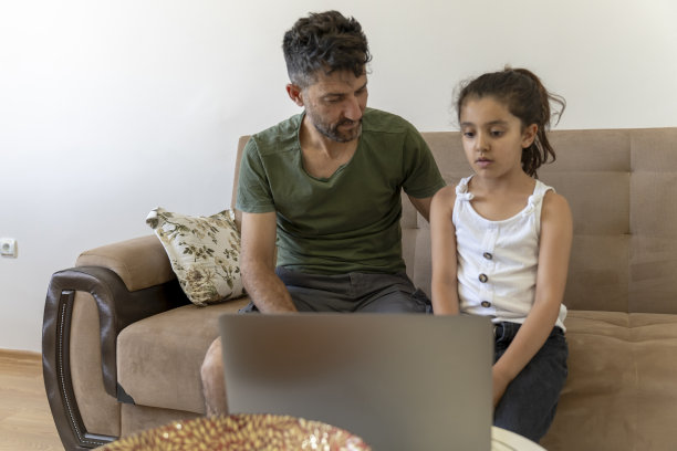 父亲和女儿在家里用笔记本电脑一起工作图片下载