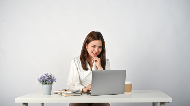 女办公室职员低头看着笔记本电脑屏幕，在办公桌前完成任务。图片下载