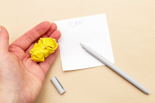 女人的手拿着皱巴巴的黄纸，上面写着在米色背景上写字的笔和便条图片下载