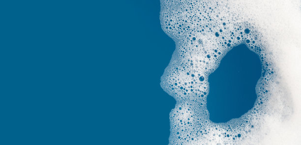 洗涤剂在水中起泡沫。蓝色背景，肥皂色图片下载