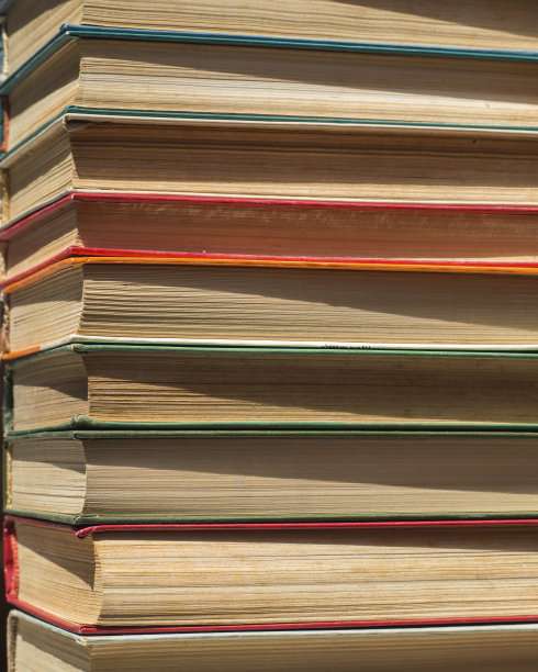 一排折叠的旧书可以用作背景。书架上有许多叠得整整齐齐的书。书脊和发黄的精装书书页图片下载