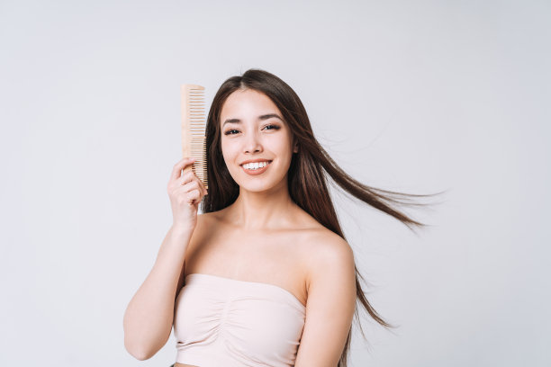 美丽的肖像快乐微笑的亚洲妇女与黑色长发梳木梳子在白色背景孤立图片下载