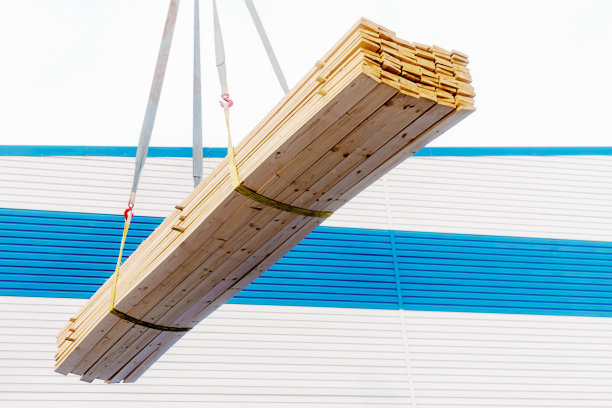 木板用吊索吊起来。夏天的下午，在外面装载木材和建筑材料。图片下载