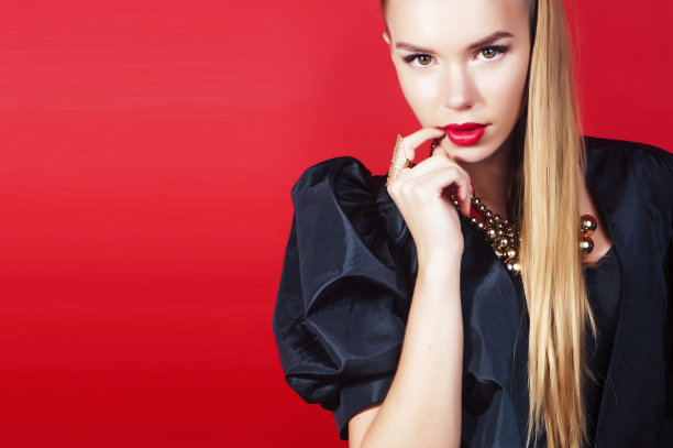 年轻漂亮的女人在红色背景上摆姿势，生活方式的人的概念图片下载