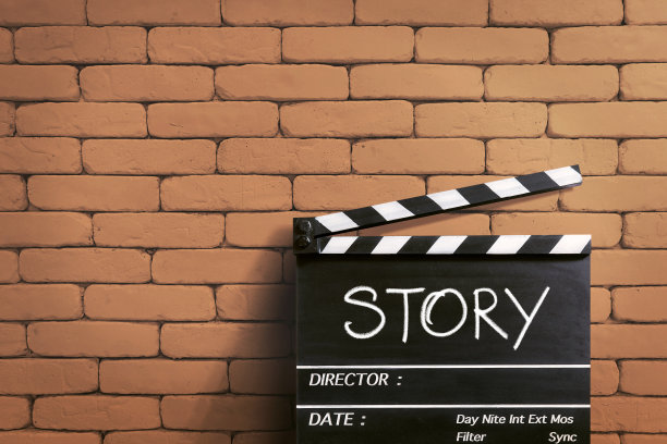 的故事。手写在隔板或电影板上。橙色砖墙。图片下载