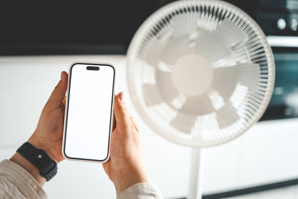手机在手，背景是电风扇，智能家居概念图片下载