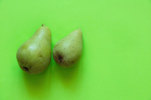 绿纸背景上的两个绿梨特写图片下载