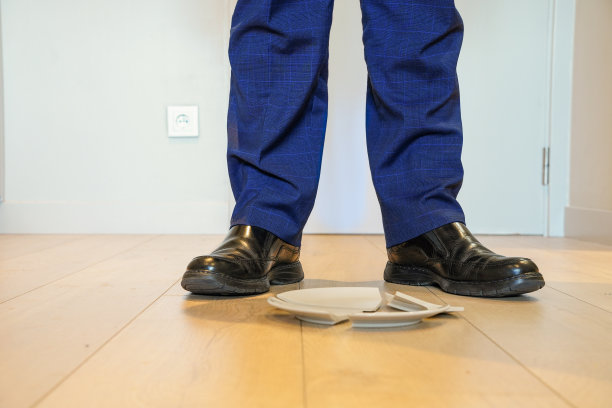 地板上一个破碎的盘子和一个商人的两条腿。厨房里的暴力和虐待。国内事故图片下载