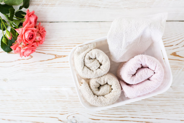 把干净的毛巾卷在一个容器里，还有一束玫瑰花。前视图。组织和秩序图片下载
