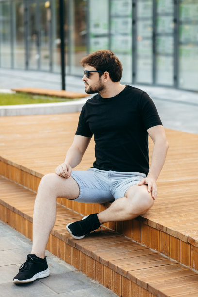 穿着黑色t恤，戴着墨镜的年轻时髦的大胡子男人。街头的照片图片下载