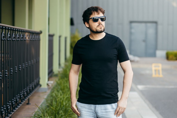 穿着黑色t恤，戴着墨镜的年轻时髦的大胡子男人。街头的照片图片下载