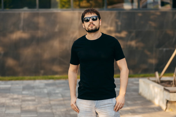 穿着黑色t恤，戴着墨镜的年轻时髦的大胡子男人。街头的照片图片下载