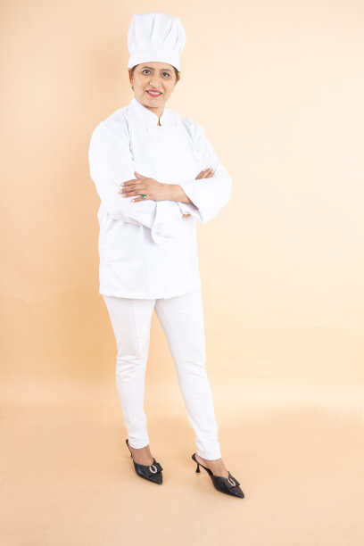 快乐的成熟女性厨师或厨师穿着制服，孤立地站在米色背景上。图片下载