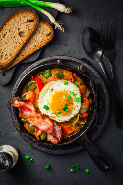 Letscho - tasty Hungarian vegetable stew with peppers, tomatoes  and onions, served with bacon and fried egg图片下载