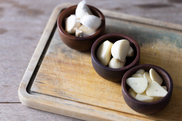 调味大蒜和香草为美味的家庭烹饪。新鲜的大蒜和各种芳香的香草在木桌上美丽地排列，唤起自然的味道和香味。图片下载
