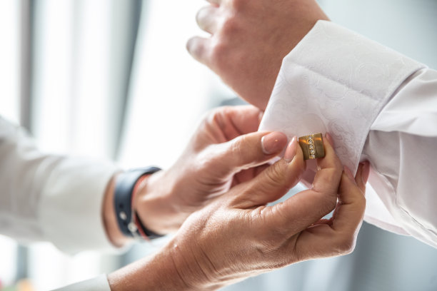 伴郎在婚礼前帮新郎固定衬衫上的袖扣。图片下载