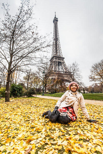 春天的巴黎，一名年轻女子在埃菲尔铁塔前摆姿势图片下载
