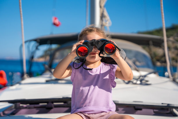 小女孩在游艇上用双筒望远镜看海图片下载