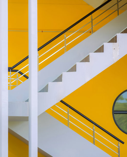 现代白色楼梯的侧面，有黑色的栏杆和黄色的墙。图片下载