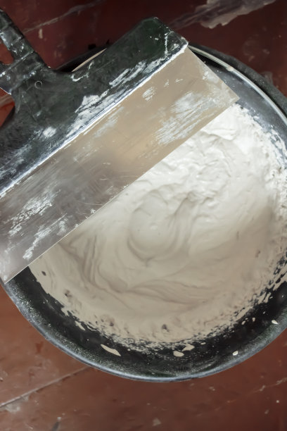 修补墙壁-在桶中解决腻子。桶里的油灰。施工用的抹刀放在一个桶上，桶里有用来涂墙的腻子。图片下载