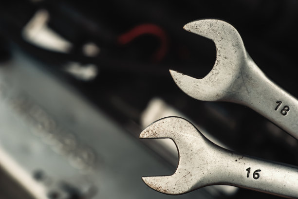 以汽车发动机为背景的扳手特写镜头。汽车商店或汽车修理店背景图片下载