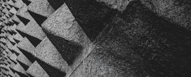 位于Juan Bravo街的La Casa de los Picos de Segovia的立面上覆盖着花岗岩纹理的金字塔形状的石头图案，背景是阳台。图片下载